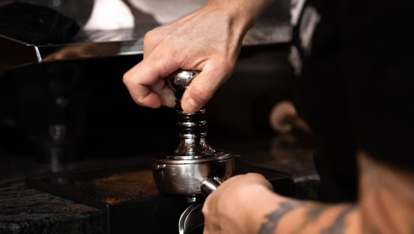 Barista pressant le café dans le porte-filtre